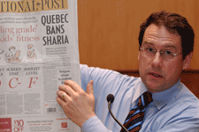 L'animateur de l'atelier, le journaliste Bernard Drainville, a orient&eacute; le d&eacute;bat avec grande aisance. Il brandit ici le National Post avec un titre fracassant, qui remettait une fois de plus au centre de l'actualit&eacute; la question des tribunaux religieux et de ce qui en d&eacute;coule pour la mouvance des femmes.